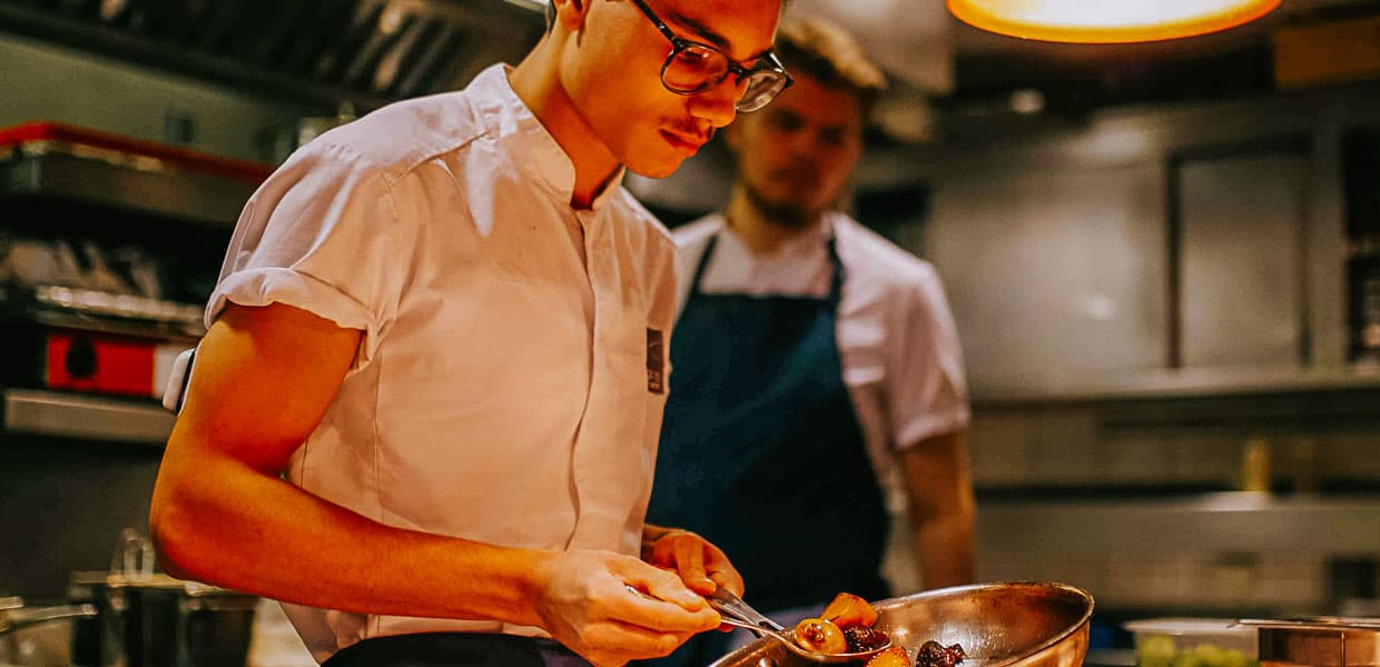 en kokk som lager mat i stekepanne på restaurant