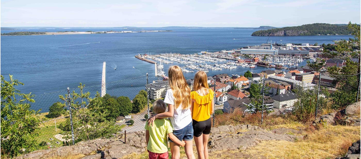 tre barn ser på sjøutsikten fra utkikkspunkt