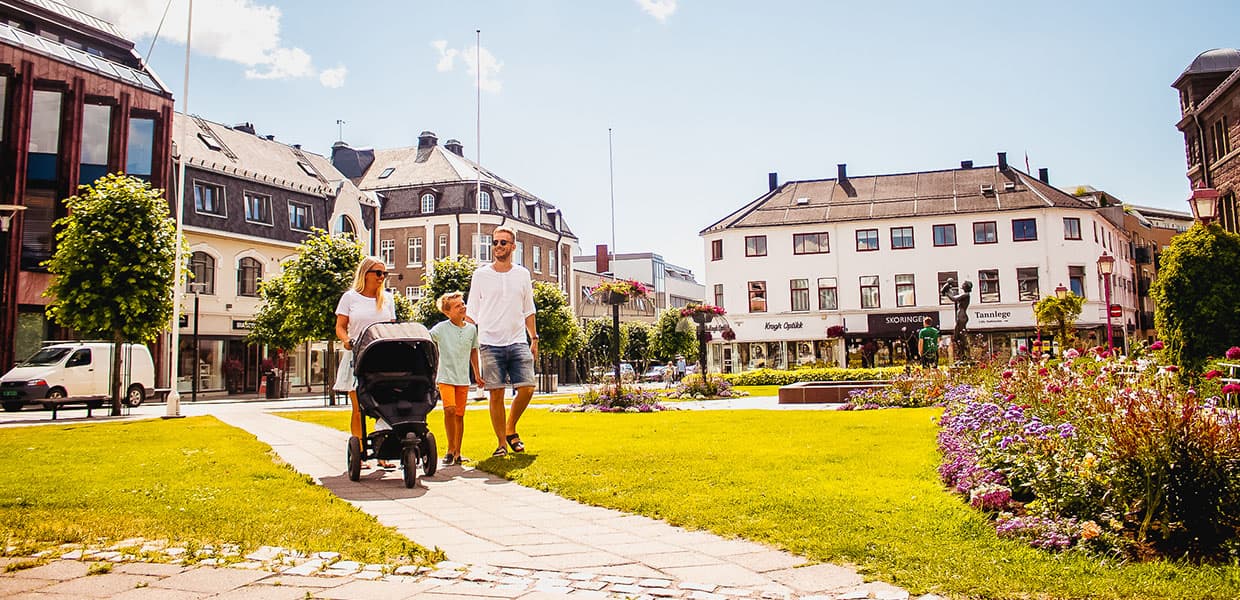 tre personer går i en bypark og triller barnevogn