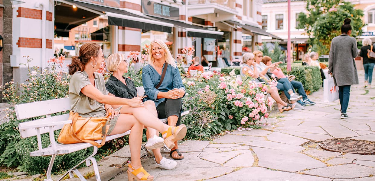 tre venner sitter på en benk i en bypark i Sandefjord