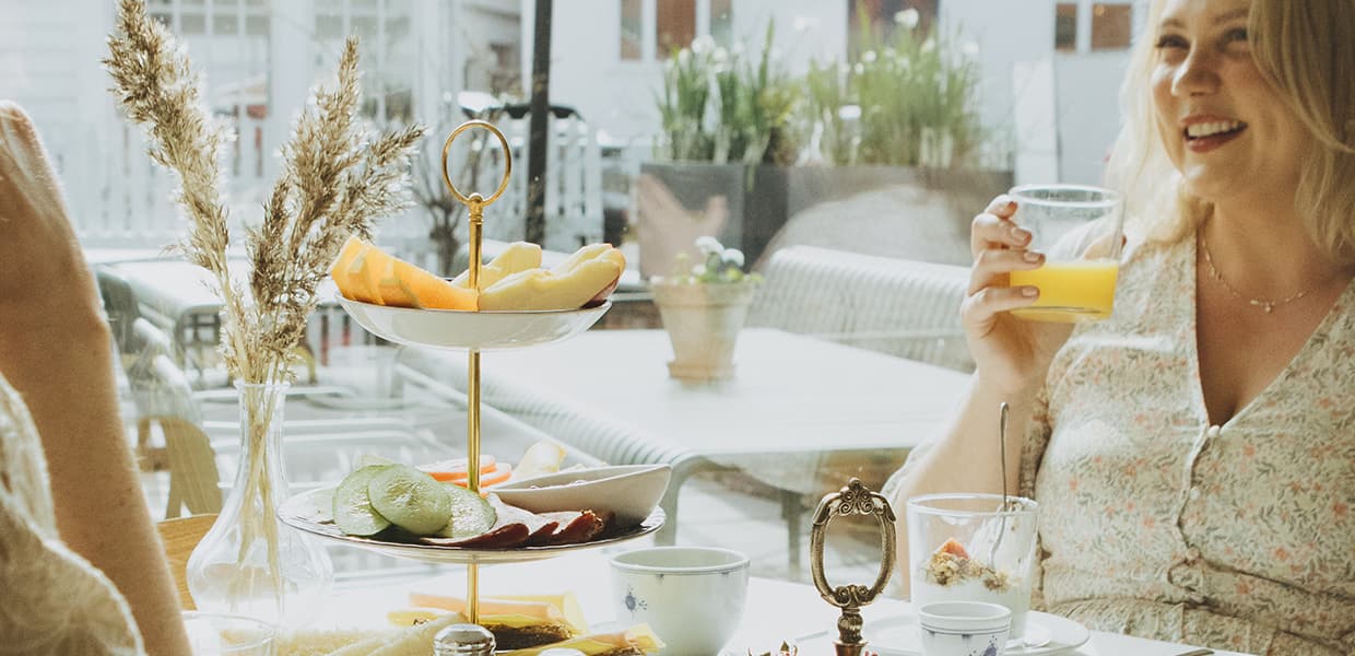 person drikker juice i restaurant med etagefat på bordet med frukt og pålegg i.